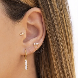 Macro view of gold S925 earrings featuring three cubic zirconia stones and chain detail