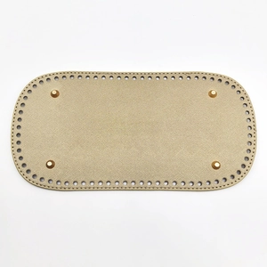 Macro view of beige textured PU leather bag bottom with pre-punched holes and gold studs