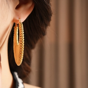 Detailed close-up of golden hoop earrings featuring a fine striped textured metal finish