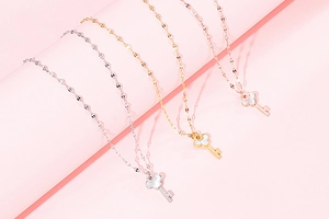 Detailed shot of three shell-inlaid key pendants in silver, gold, and rose gold finish