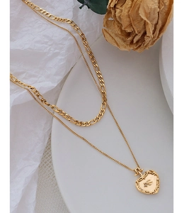 Détail du collier double rang doré avec pendentif cœur gaufré et une pierre en zircon