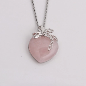 Silver bow necklace with pink heart-shaped crystal stone pendant on grey background