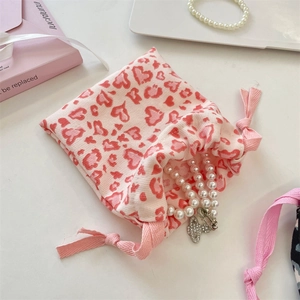 Detail of pink leopard heart drawstring pouch with soft woven texture and jewelry