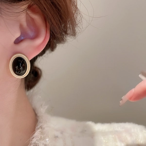 Close-up of vintage oval black gemstone earrings with golden braided texture on model