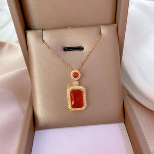 Luxury gold titanium necklace with a red rectangular gemstone pendant in a brown gift box