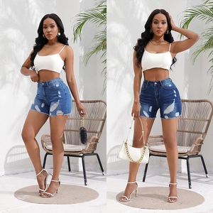 Outdoor shot of high waist distressed denim shorts with frayed edges and ripped details