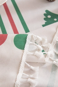 Close-up of beige linen tablecloth featuring red stripes and white tassel lace details