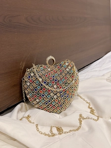 Chic heart-shaped evening bag with colorful rhinestones and gold chain strap in a still life view