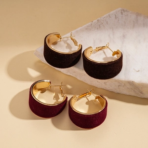 Retro geometric flocked hoop earrings in brown and burgundy velvet on stone display