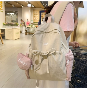 Detail of beige and pink washed fabric backpack with heart-shaped coin purse attachment