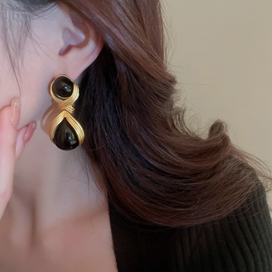 Detail of vintage black acrylic drop earrings with gold-toned metallic twisted frame