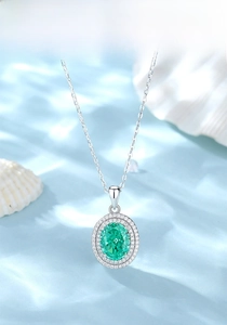 Close-up of an oval emerald green pendant with double halo diamonds on silver chain