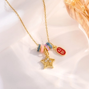 Detailed shot of gold necklace with star charm, rainbow bead, and red lucky pendant