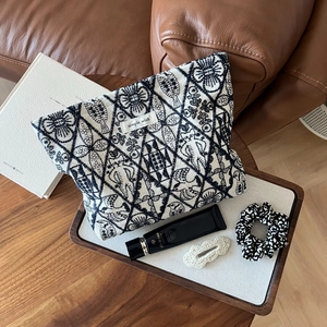 Detail of hand-embroidered cotton linen makeup bag with cat and fish woven patterns