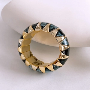 Detailed macro of gold geometric bracelet with teal marble texture on white stone