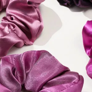 Close-up of satin silk scrunchies in purple and magenta with a glossy finish