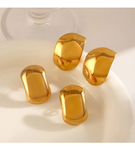 Detailed view of four polished gold-plated geometric stud earrings in a white ceramic dish