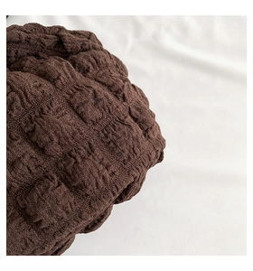 Close-up of deep brown bubble crinkle fabric texture showing elastic embossed pattern
