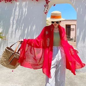 Red long silk shawl with gold floral embroidery shown in a luxury beach resort setting