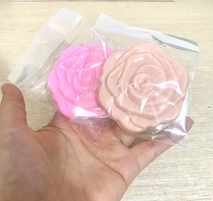 Pink and beige rose-shaped pocket mirrors in packaging on a wooden surface