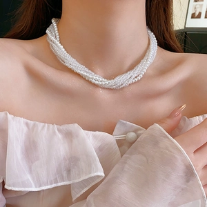 Detail of bohemian multilayer pearl necklace styled with an elegant pink ruffled top