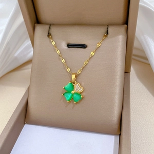 Detail of four-leaf clover pendant with green stones and gold chain in jewelry box