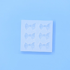 Vue détaillée du moule carré en silicone blanc avec six cavités en forme de nœud pour fondant