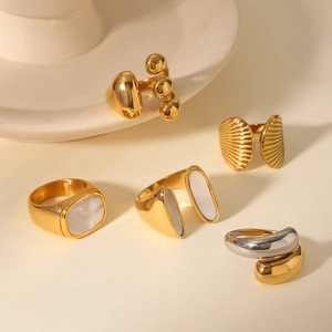 Detail of diverse stainless steel gold rings featuring white shell inlay and modern textures