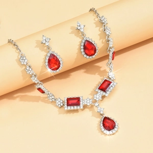 Macro shot of silver jewelry set featuring red pear-shaped gems and sparkling rhinestones