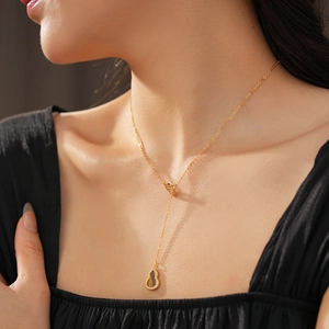Close-up of golden gourd pendant necklace with yellow zircon on a model's neck