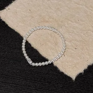 Detailed macro view of an elegant pearl bracelet with a sparkling zircon charm on a card