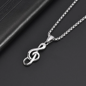 Macro shot of silver musical treble clef pendant with box chain on dark surface
