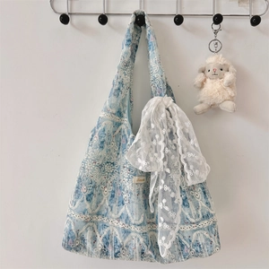 Detail of blue floral tote bag featuring white lace overlays and a decorative lace bow