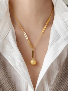 Detail of elegant gold necklace featuring a matte finish round pendant and link chain