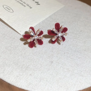 Macro detail of red flocked flower stud earrings with pearls and crystals on linen