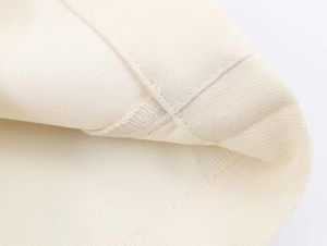 Dettaglio della cucitura a trama piana di alta qualità su questi pantaloni larghi crema