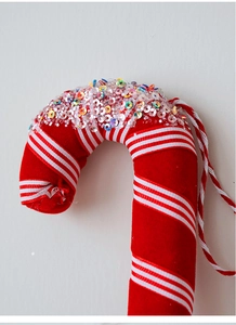 Detail of red and white striped Christmas candy cane with colorful glitter sequins