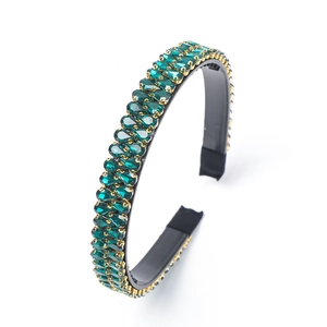 Baroque gold headband with sparkling green crystals on a black base for women