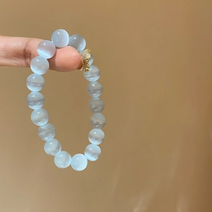 Detail view of light blue cat-eye beaded bracelet with a cute golden bear pendant charm