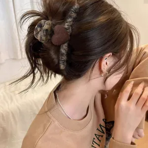 Detail view of a brown heart hair claw clip with flocking texture on model's hair