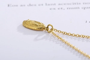Vue latérale macro du pendentif ovale doré avec relief religieux et texture métallique