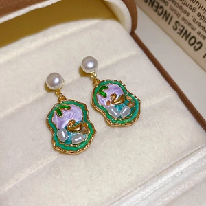 Macro detail of vintage swan enamel earrings with white pearls and gold metal finish