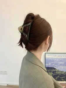 Detail of a dark grey transparent triangular hair claw clip worn on a model's hair