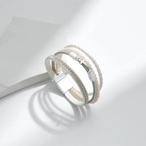 Detailed macro shot of a white multi-layer woven bracelet with silver cross pendant