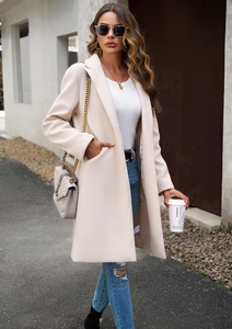 Street style shot of a beige long wool coat with lapels and pockets in a city setting