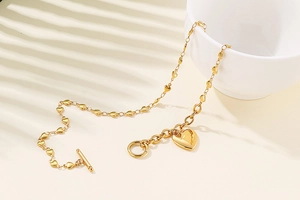 Detail of golden stainless steel heart bracelet with toggle clasp and heart charm