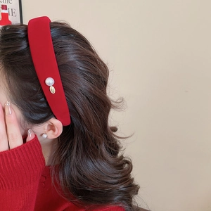 Detail view of red velvet headband with pearl and gold pendant on wavy hair