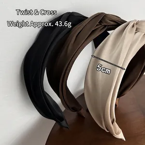Three elegant twisted cross headbands in black, brown, and beige with a satin finish