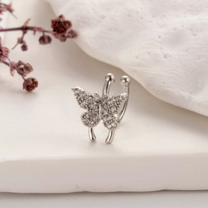 Macro detail of silver butterfly ear cuff with micro-pave cubic zirconia on stone stand