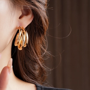 Gros plan de boucles d'oreilles dorées en C multicouches sur un modèle élégant